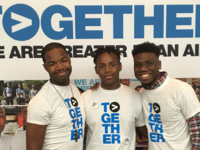 Three men smiling with Greater Than AIDS shirts at USCA 2017