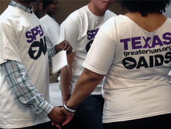 Men and women holding hands wearing Greater Than HIV shirts