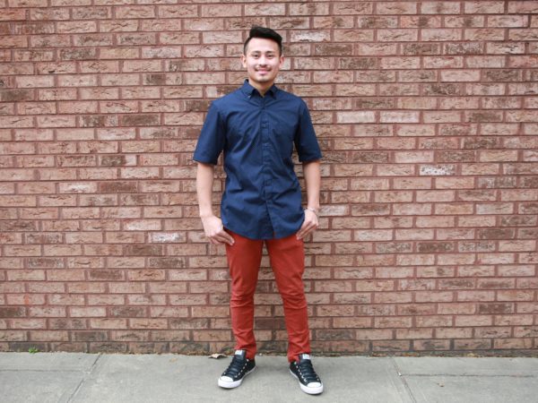 Man smiling against a brick wall