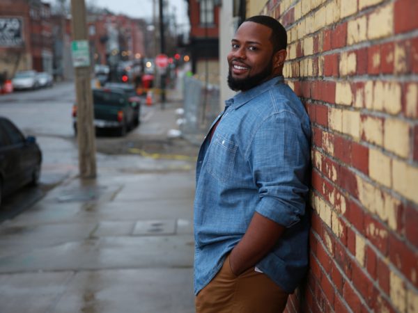 Man smiling leaning against a wall