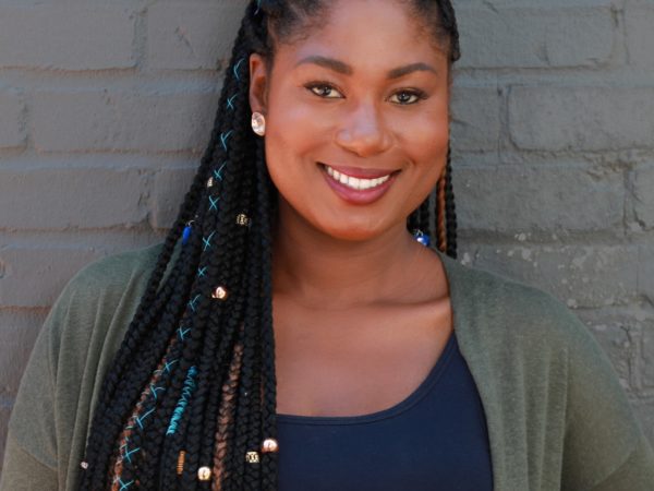 Person smiling at camera against gray wall