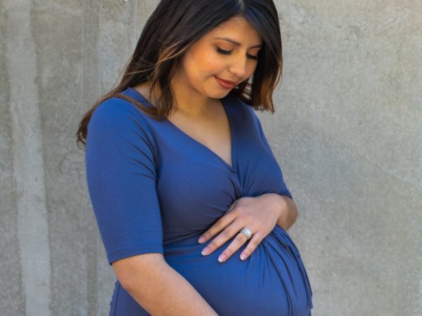 Smiling pregnant woman holding her stomach and looking down