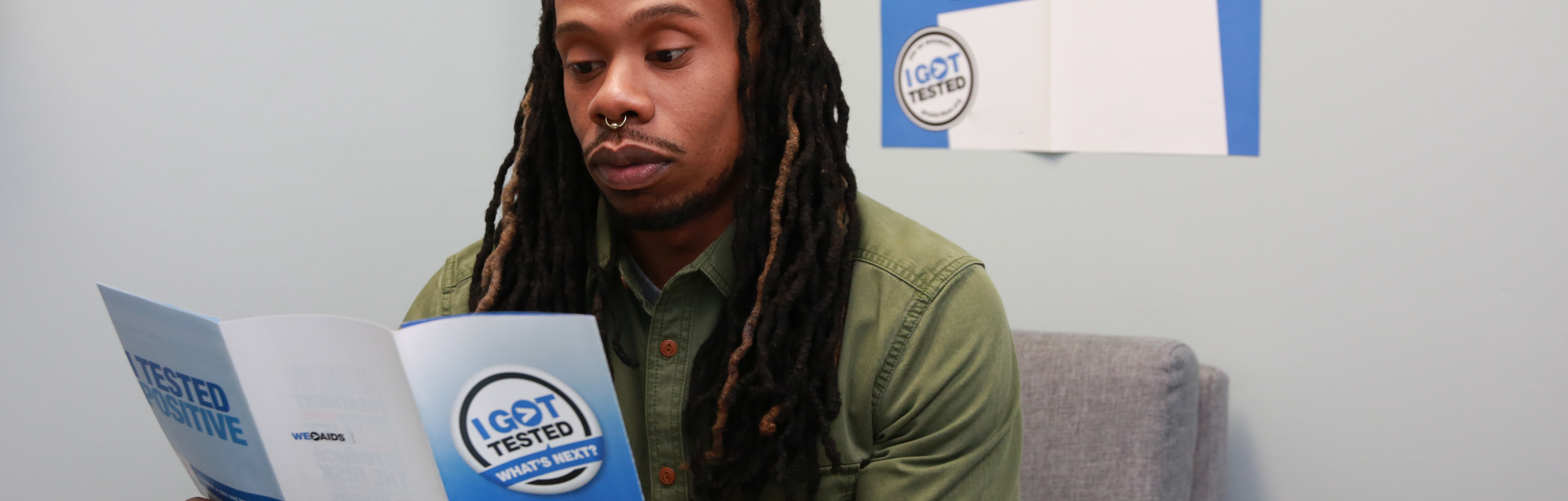 Man sitting in a pharmacy reading an, "I got tested, what's next?" brochure