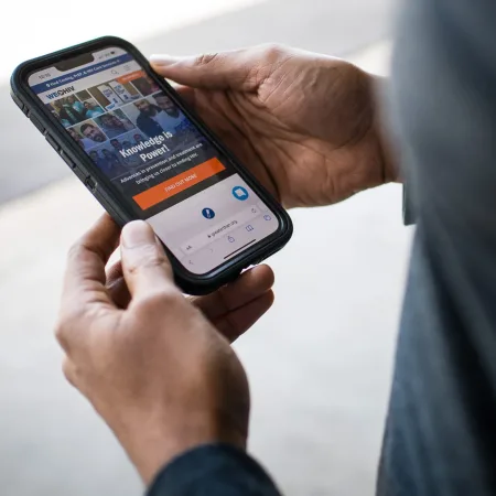 Hands holding phone with a website on the screen